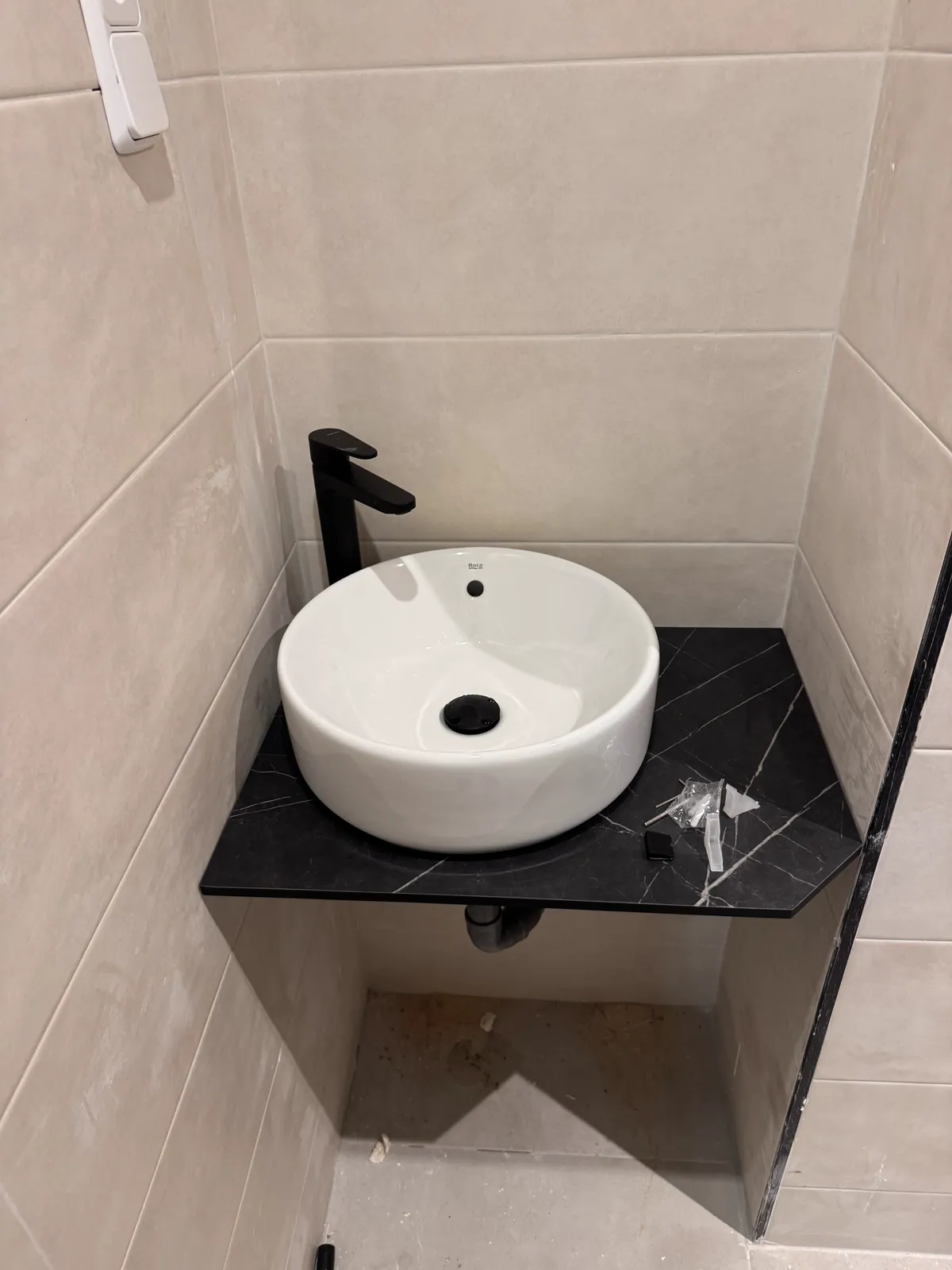 Lavabo sobre encimera negra con grifería alta instalado