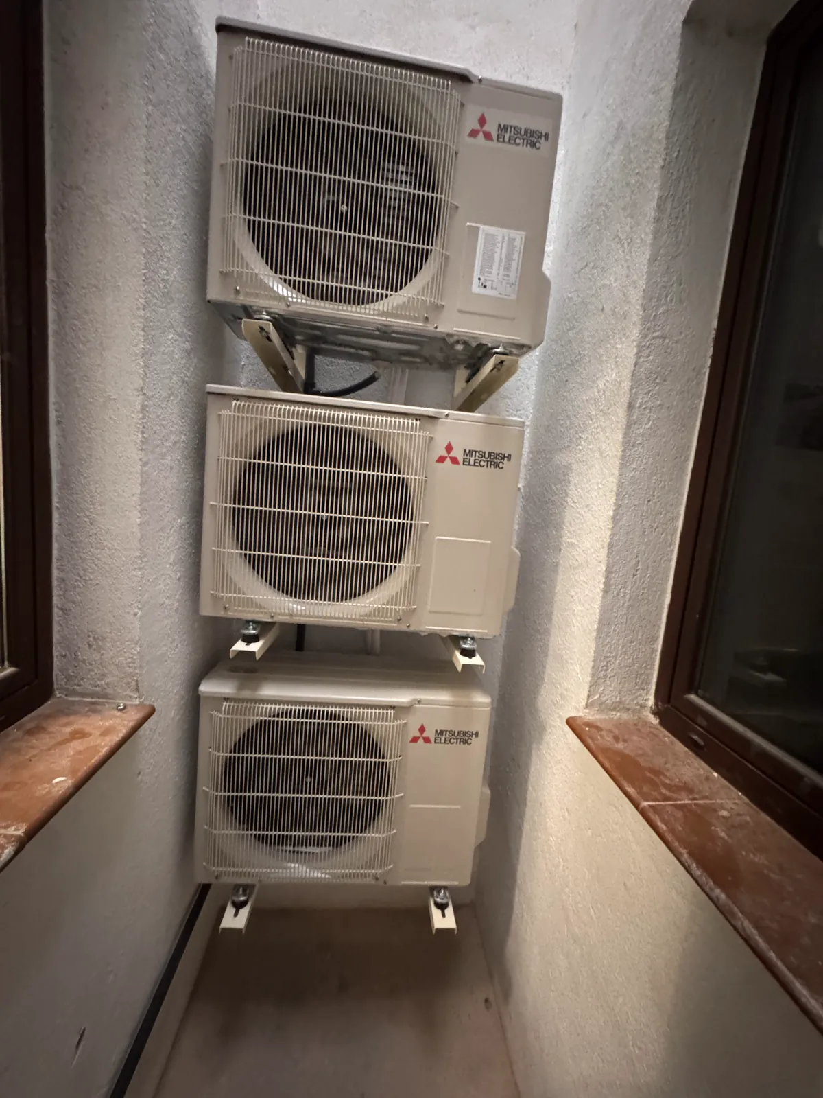 Tres unidades exteriores de aire acondicionado Mitsubishi instaladas en un patio interior
