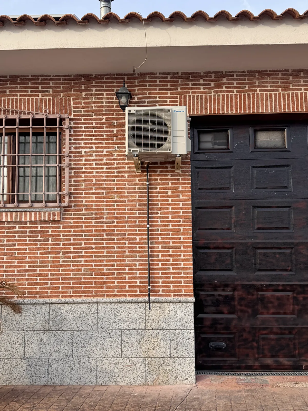 Unidad exterior de aire acondicionado instalada en fachada de ladrillo