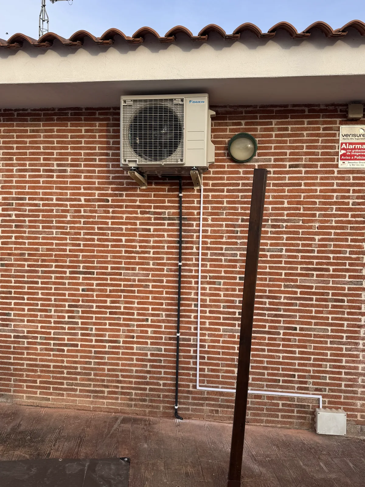 Unidad exterior de aire acondicionado con canalización vista en fachada