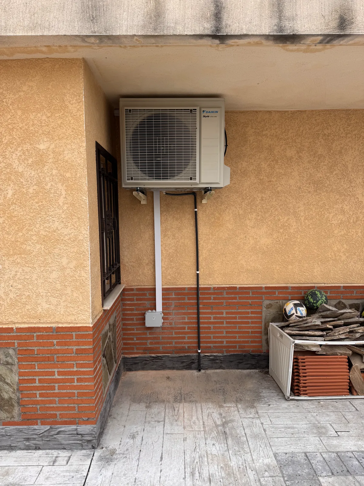 Unidad exterior de aire acondicionado instalada en una pared de patio