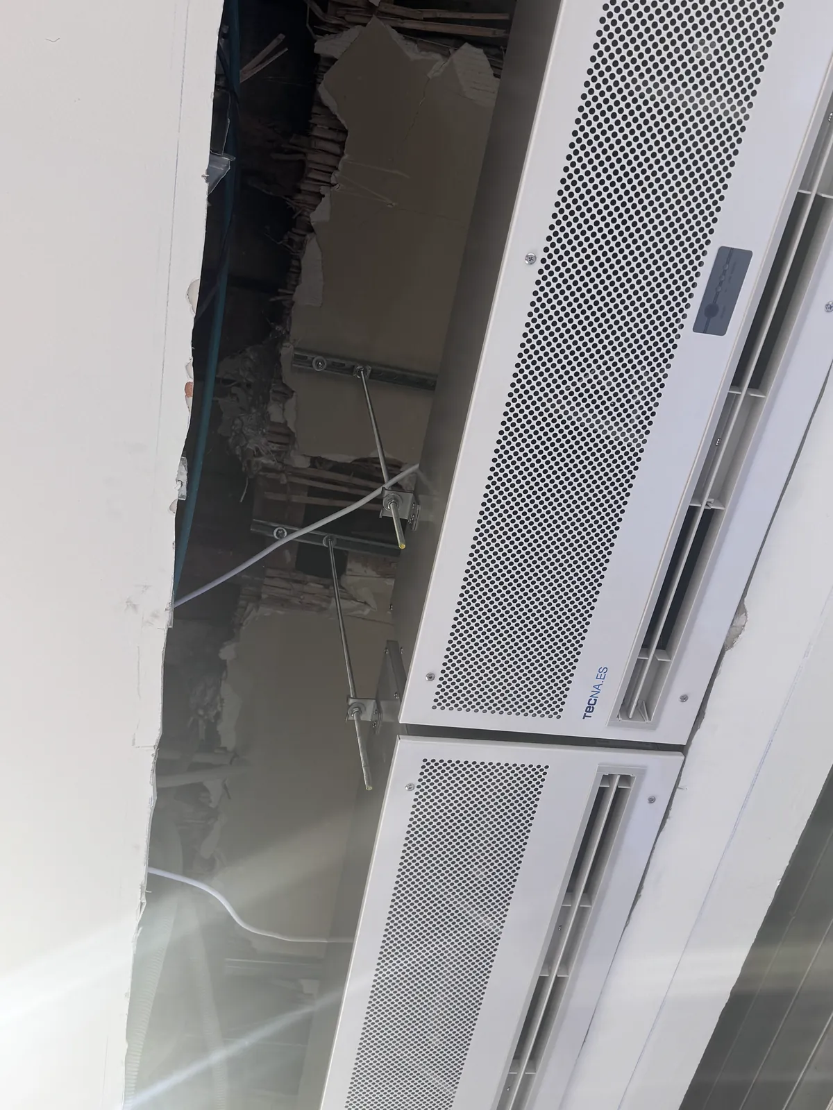 Equipo de climatización de conductos con rejilla perforada instalado en el techo