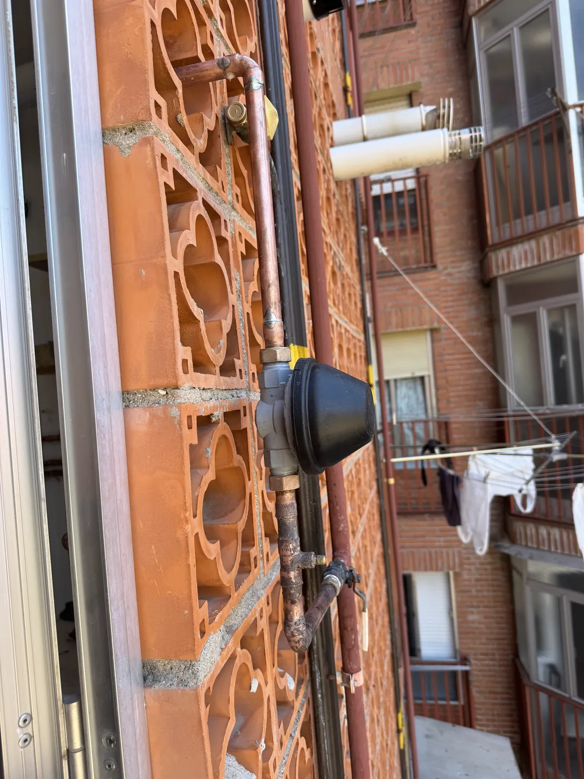Regulador de gas y tubería en la fachada de un edificio
