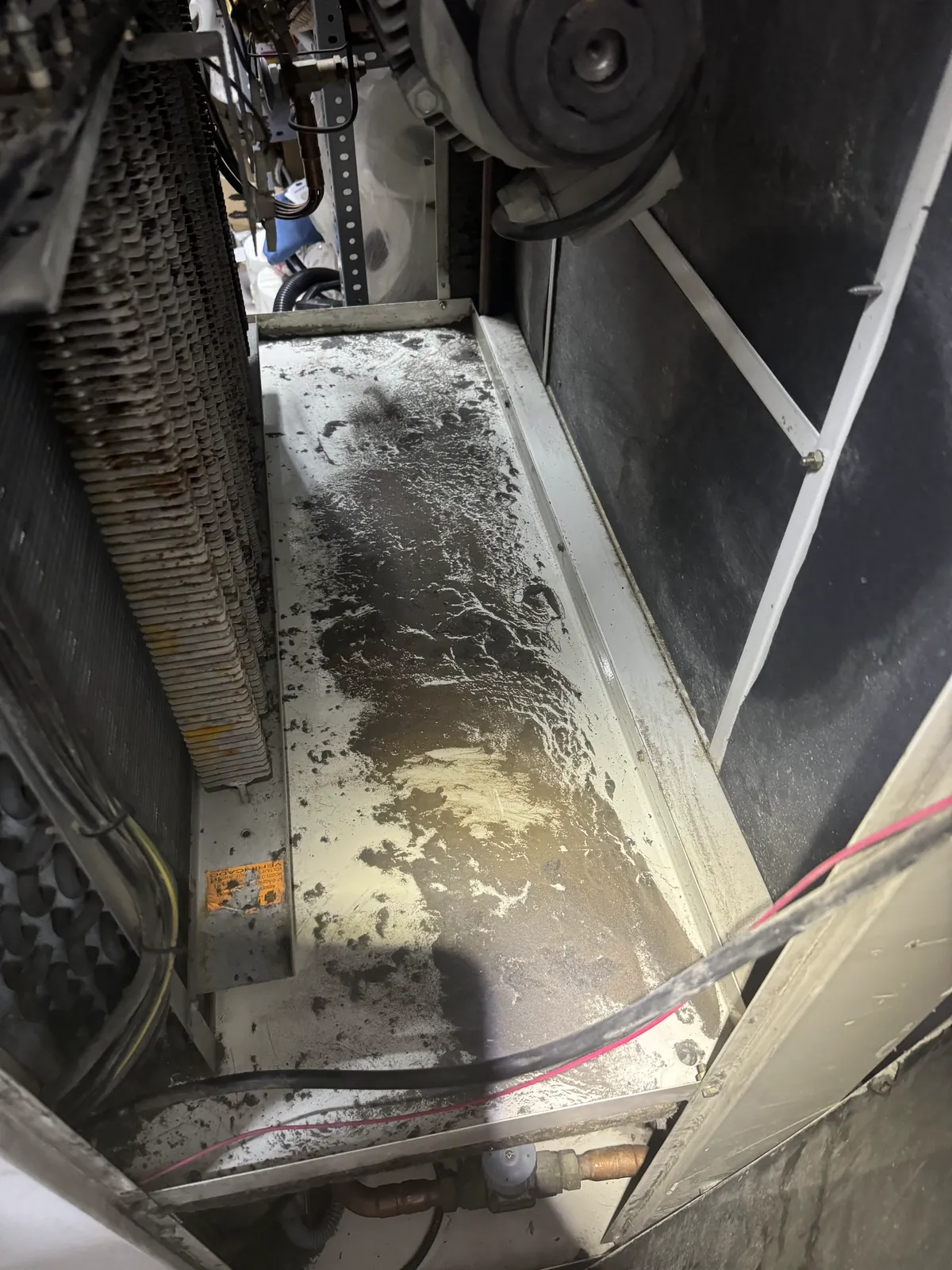 Interior de una climatizadora durante la limpieza de la bandeja y las baterías